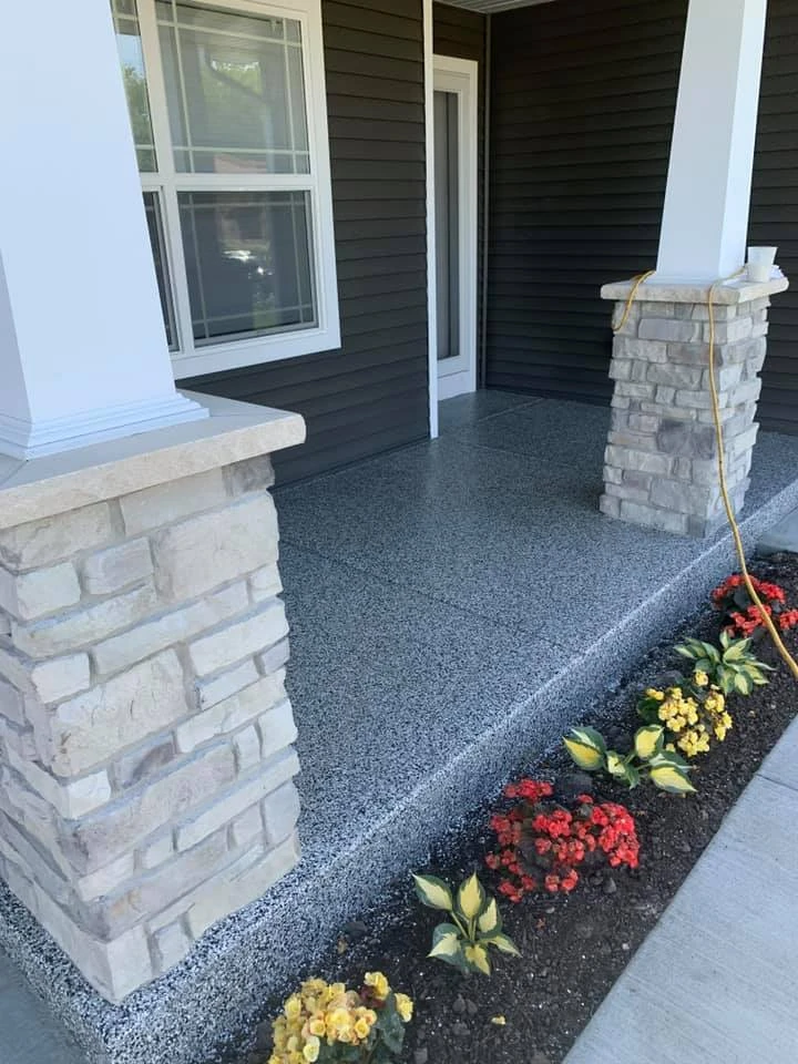 Covered front porch with a gray flake concrete coating between stone columns