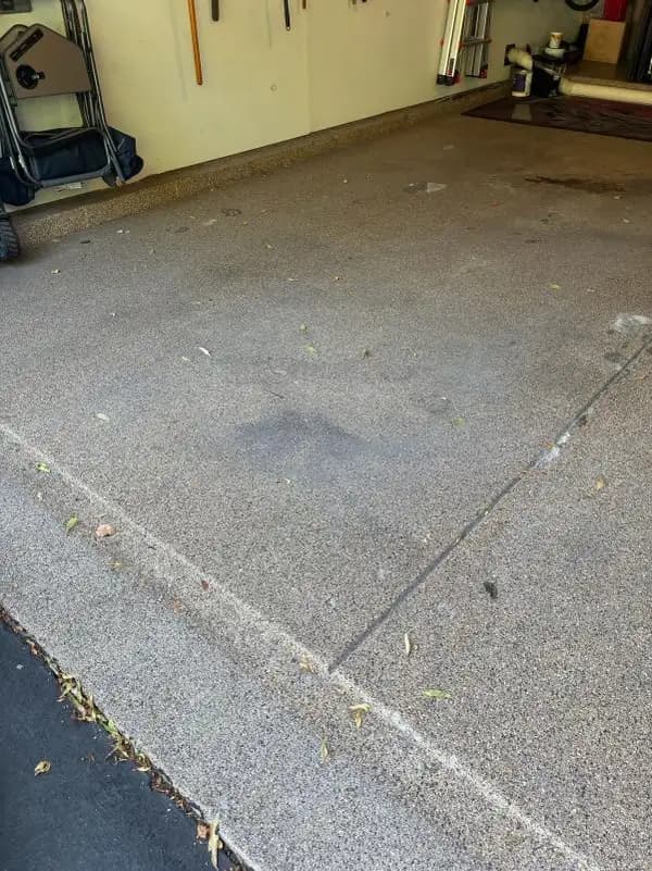 Old flake garage floor coating with dark tire staining and coating missing along the control joint