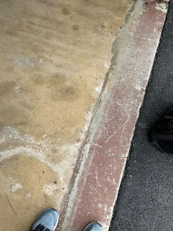 Old yellowed garage floor coating worn through and peeling away along the garage door threshold