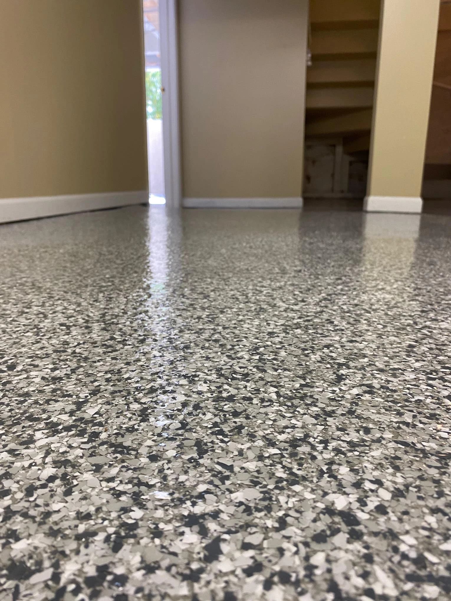 Close-up of a finished basement floor with gray and black decorative epoxy flake