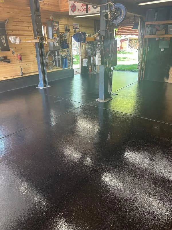 Auto shop with vehicle lifts on a dark metallic floor coating