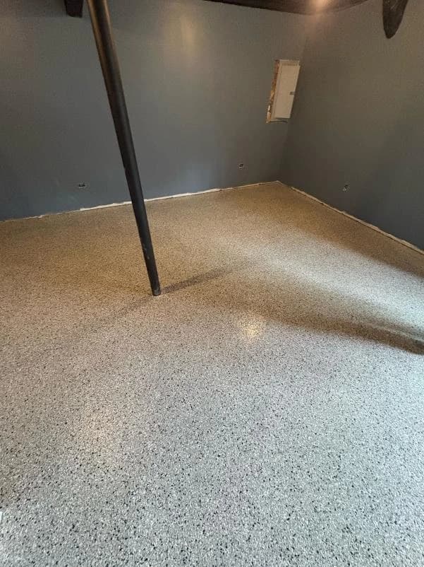 Basement corner with a gray flake floor coating and dark painted walls