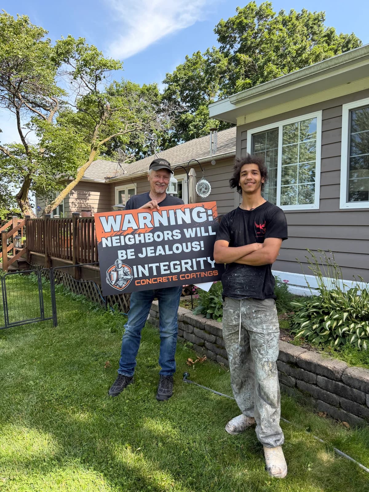 Homeowner and Integrity crew member holding a Neighbors Will Be Jealous sign in a front yard