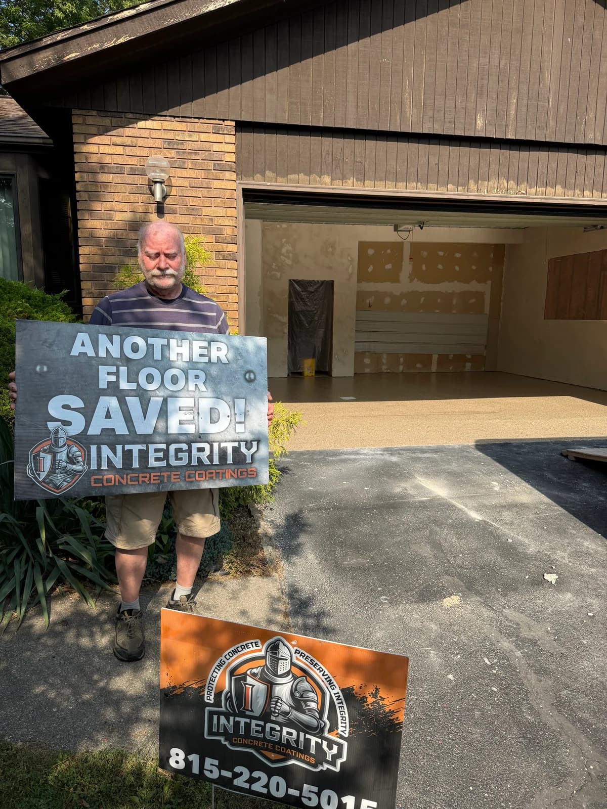 Customer with an Another Floor Saved sign in front of a garage during a coating installation