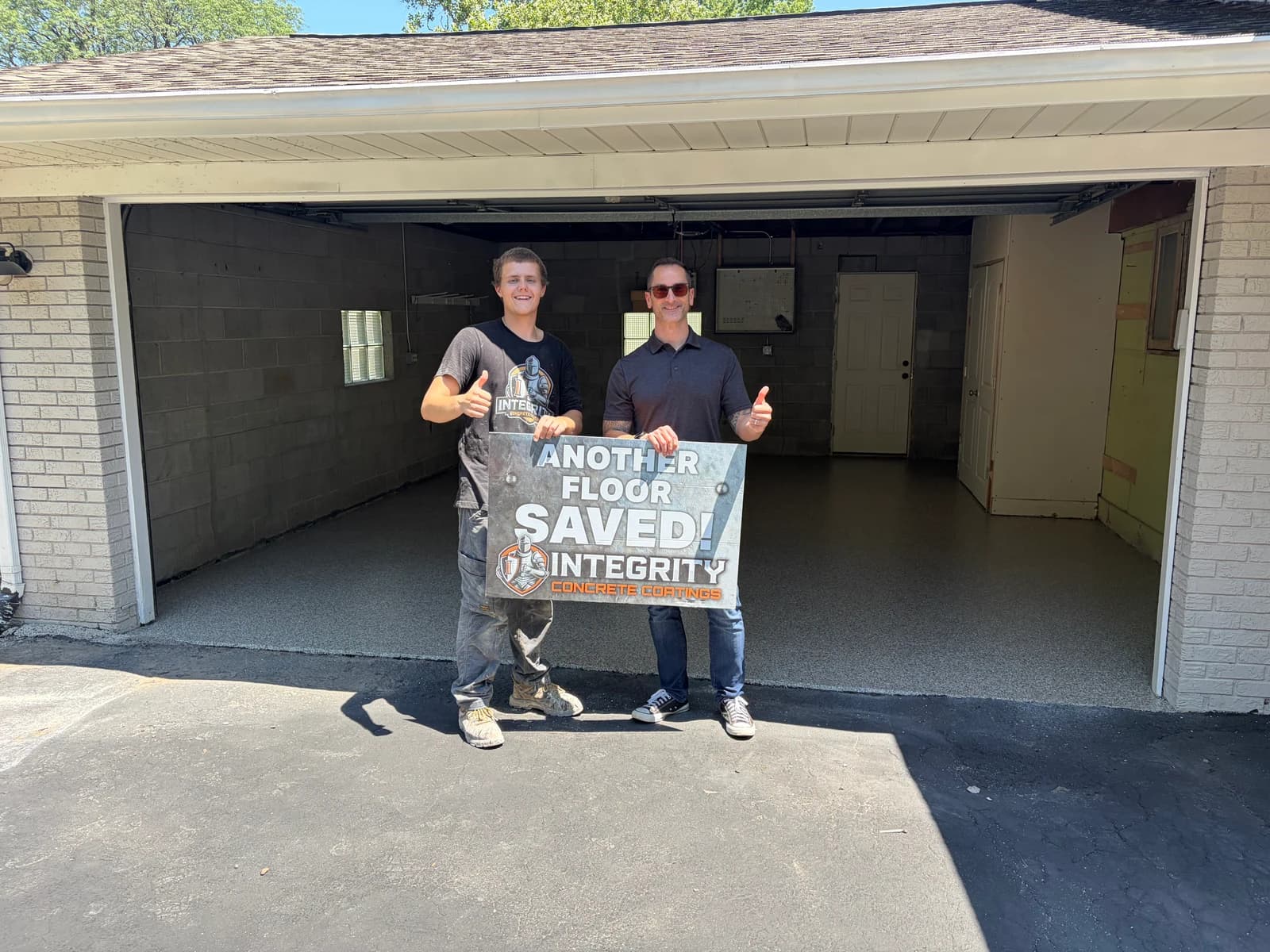 Crew member and homeowner giving a thumbs up with an Another Floor Saved sign at a coated garage