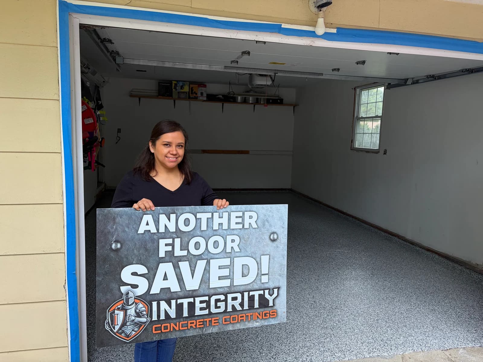 Customer holding an Another Floor Saved sign in a single car garage with flake floor coating