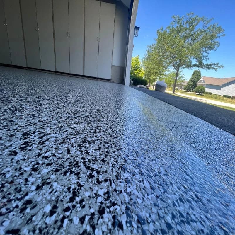 Garage floor coated with a blue and black flake blend beside storage cabinets