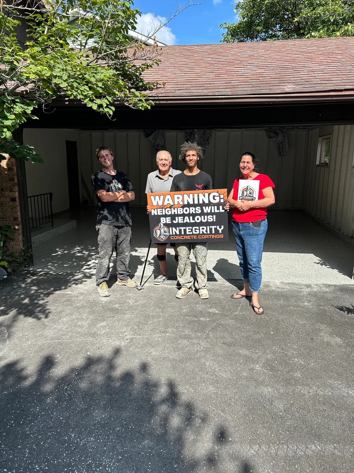 Integrity crew and homeowner outside a garage with a newly coated concrete floor