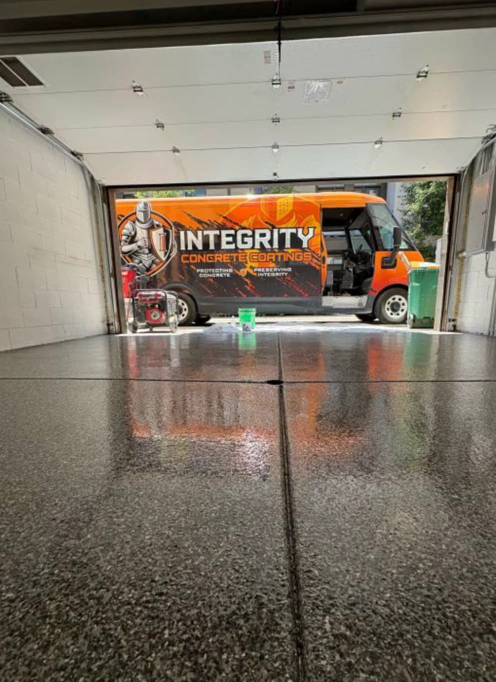 Freshly coated garage floor with an Integrity Concrete Coatings service truck in the driveway