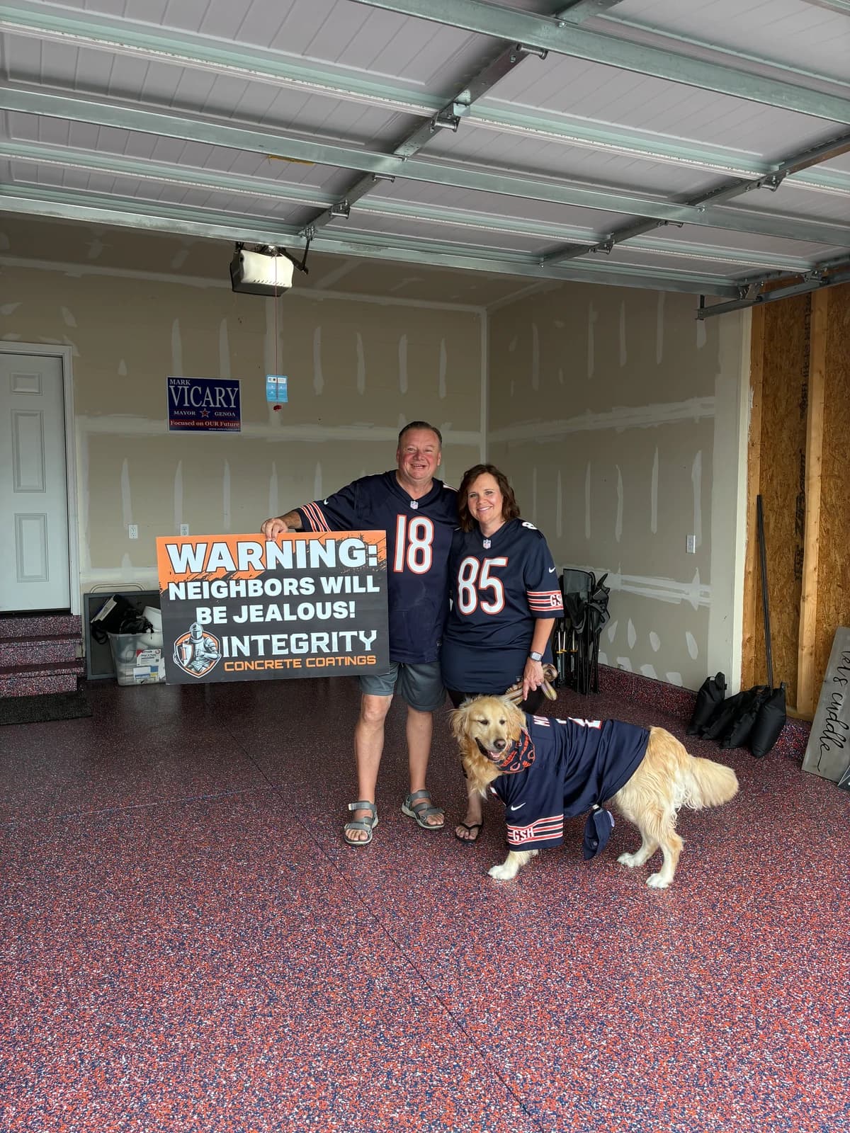 Couple and dog in team jerseys on a navy and orange flake garage floor coating