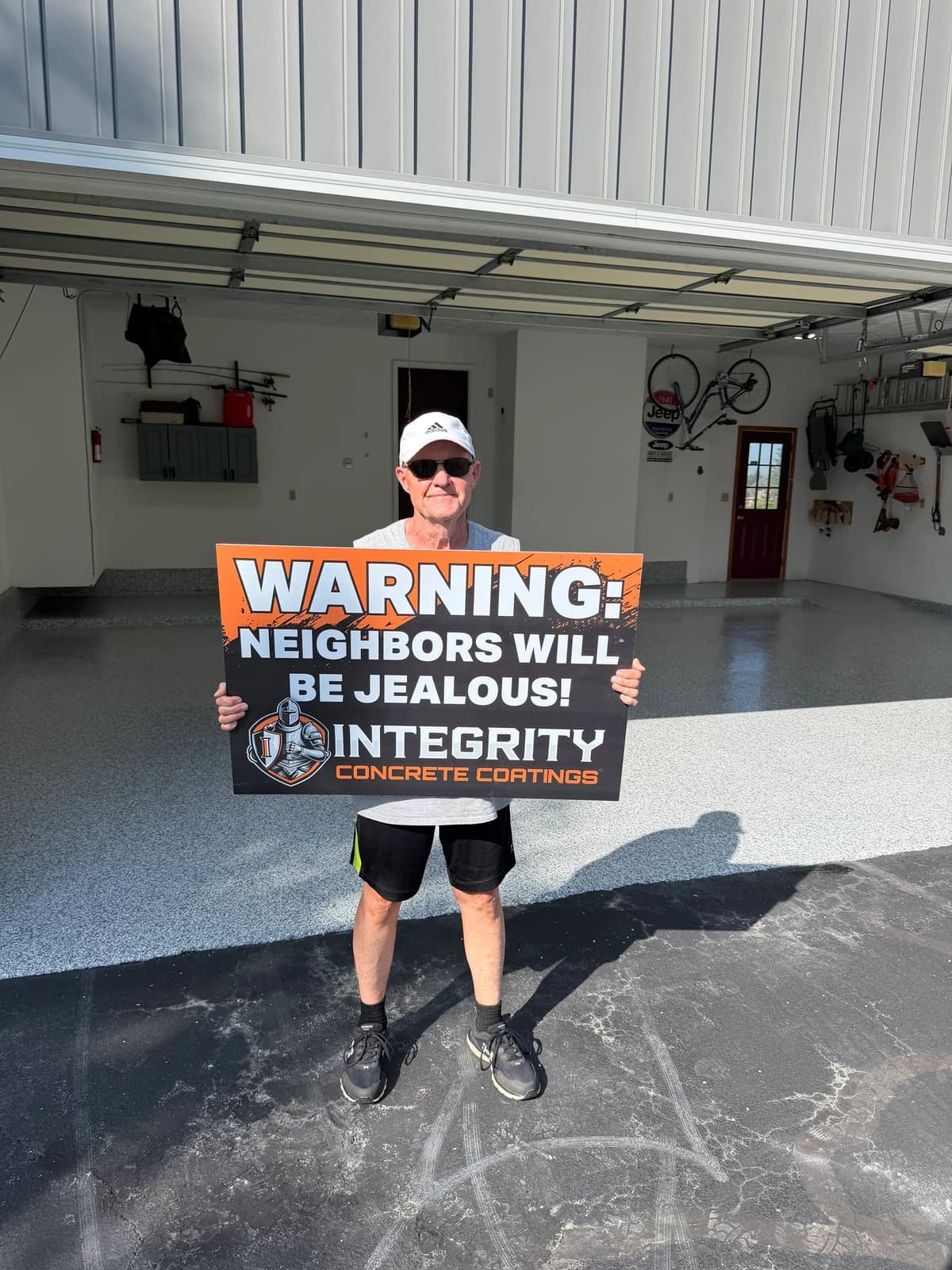 Customer with a Neighbors Will Be Jealous sign inside a flake coated garage