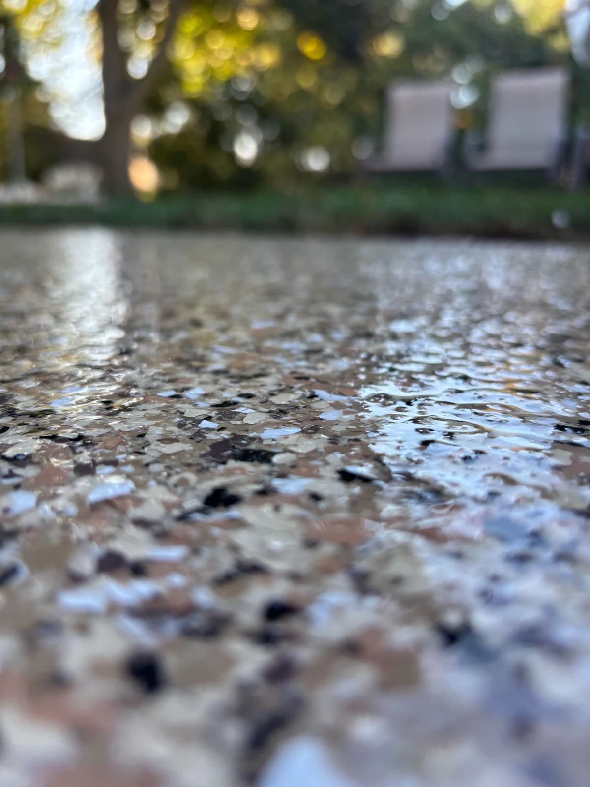 Close-up of a flake concrete coating on a backyard patio at dusk