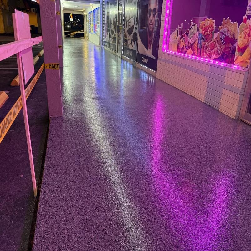 Pickleball facility concourse with a flake concrete coating under accent lighting
