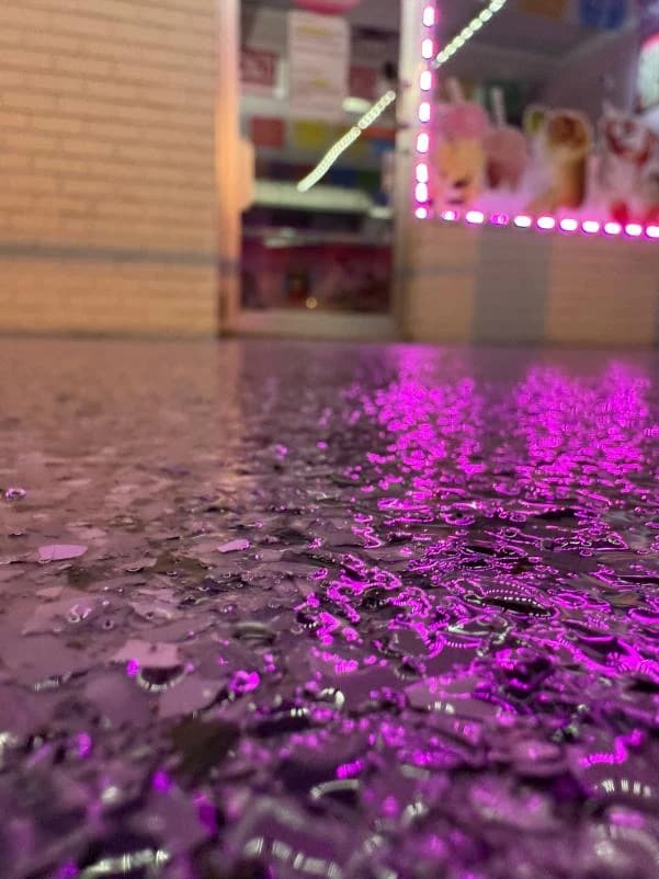 Close-up of a flake concrete coating under colored lighting at a pickleball facility