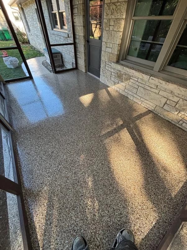 Screened porch with a stone facade and a gray flake concrete coating