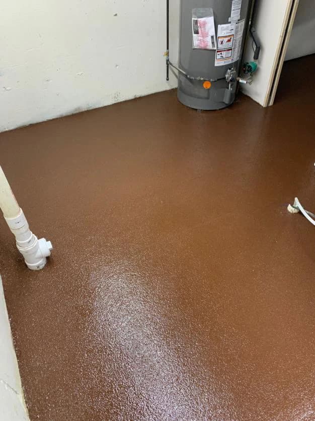 Utility room with a brown flake floor coating around the water heater