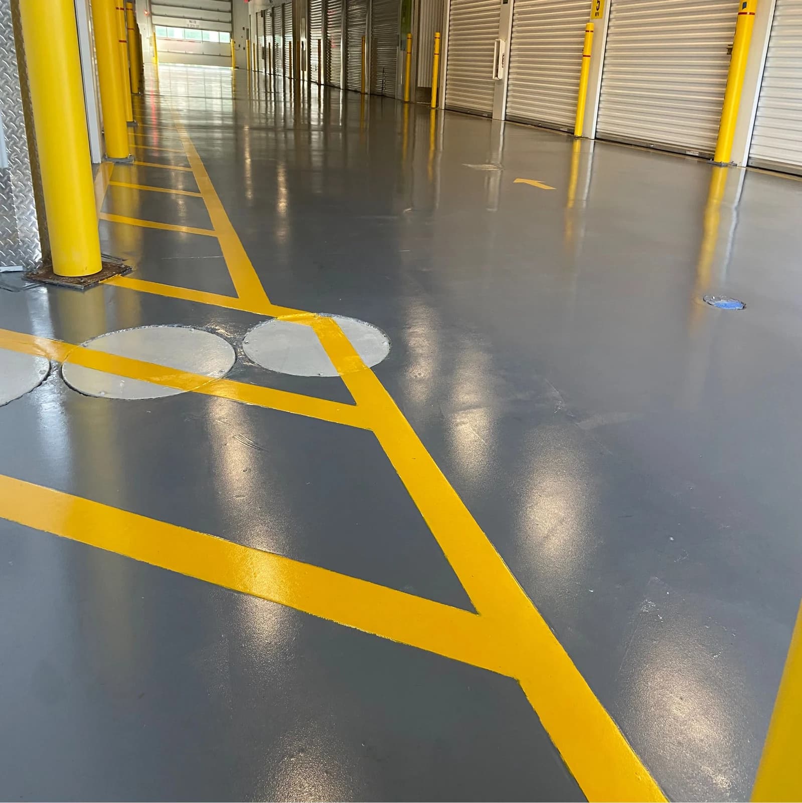 Warehouse floor coating with bright yellow safety striping and traffic markings