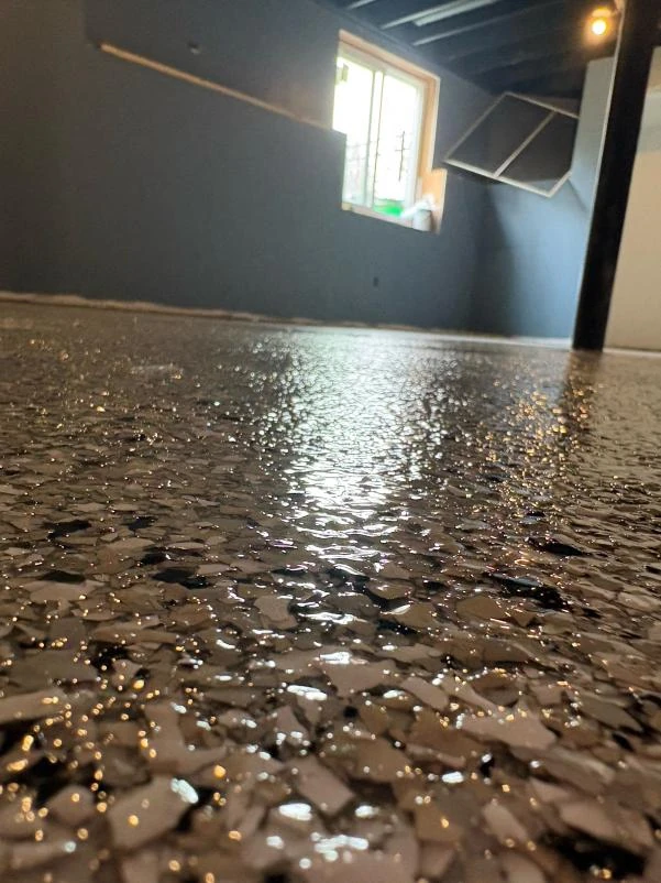 Close-up of a glossy dark flake epoxy basement floor in a Northern Illinois home